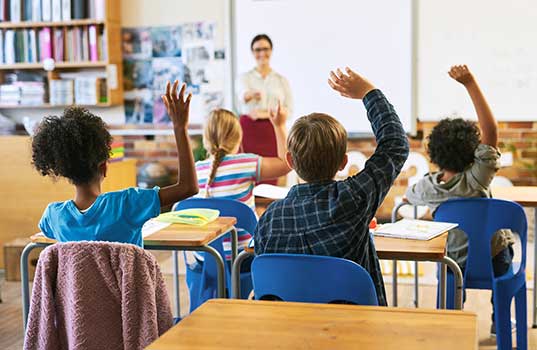 Classroom with children raising their hands